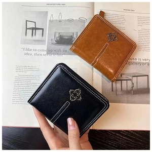 Close-up of a stylish short wallet with contrast stitching and floral metal buckle detail