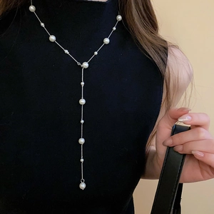 Detail of elegant pearl tassel necklace with silver chain on a black turtleneck sweater