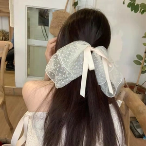 Detail of a large cream polka dot mesh bow hair clip with long ribbons on hair