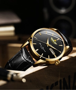 Close-up of luxury gold men's quartz watch with black leather strap and double calendar dial