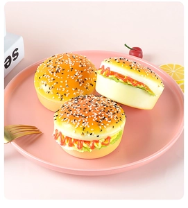 Three realistic PU squishy burgers with sesame seeds and sauce on a pink tray
