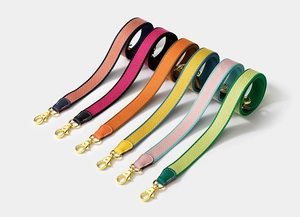 Detail of woven canvas bag straps in various colors with leather ends and gold hooks