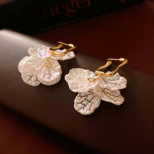 Macro detail of pleated acrylic flower earrings with iridescent finish and gold plating