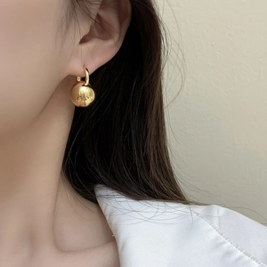 Minimalist gold ball drop earrings worn by a model to show elegant style and scale