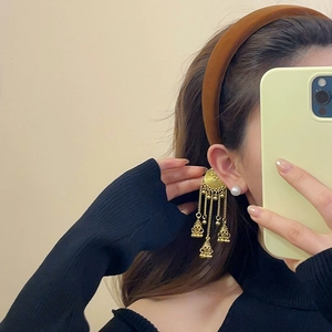 Detail of ethnic golden multi-layer tassel earrings and white pearl stud on ear