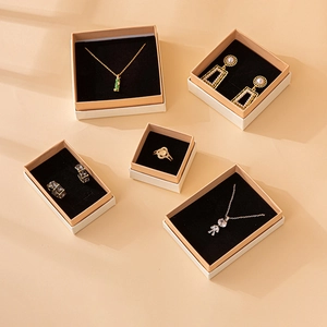 Chic beige jewelry gift boxes with black lining displaying gold and silver necklaces and rings
