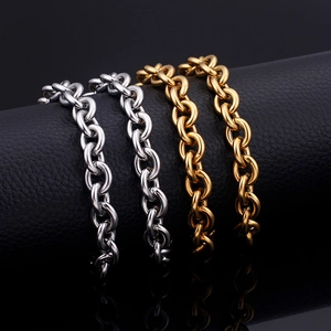 Polished gold and silver stainless steel cable chains on black leather background