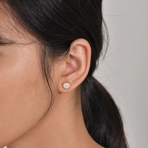 Minimalist round stainless steel earrings with white mother of pearl inlay on model ear