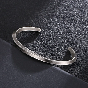 Bracelet jonc torsadé en acier argenté vintage sur fond de cuir noir texturé