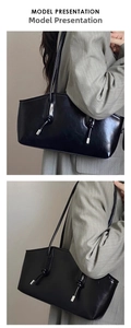 Detail of a large black glossy tote bag styled with a grey striped blazer on a model