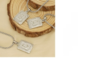 Detail view of stainless steel square letter pendants on a classic box chain necklace
