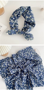 Detailed view of blue floral square neck scarf shown tied and folded on white surface