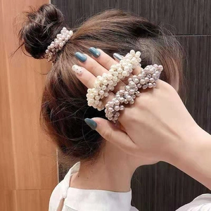 Elegant beaded pearl hair ties in cream and champagne colors worn by a female model