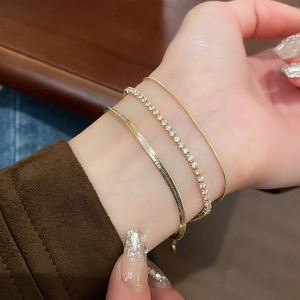 Detail shot of a three-piece gold snake and tennis bracelet set with zircon on a wrist