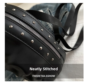 Macro view of black leather bag featuring silver metal rivets and a sturdy metal zipper