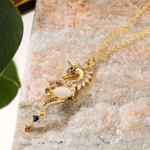 Detailed close-up of golden dragon pendant with white stones on natural stone base
