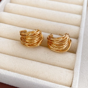 Close-up of gold-plated multi-layer C-shaped twisted earrings on a jewelry box