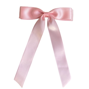 Close-up of pink satin ballet style double bow hairclip with glossy texture and long ribbons