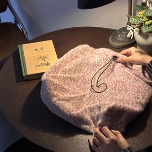 Detail showing hands pulling the drawstring closure of the pink leopard plush bag