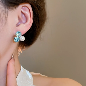 Close-up of 18k gold plated cluster earrings with blue crystals and white pearls