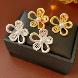 Détail de boucles d'oreilles fleurs en maille dorée et argentée avec perles sur écrin
