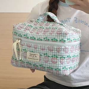Detail showing hand-held blue checkered quilted toiletry bag with floral berry prints