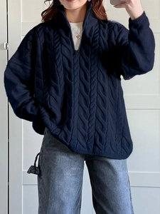 Detail of dark blue cable knit sweater with half-zip collar worn in a casual lifestyle setting