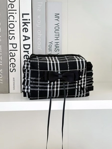 Détail de la pochette à carreaux noir et blanc avec nœud et bords à volants élégants