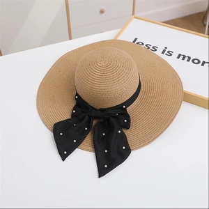Detailed view of women's straw sun hat with large black ribbon bow and pearl accents