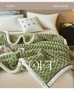 Detail of green fleece blanket with popcorn texture and soft plush material on a bed