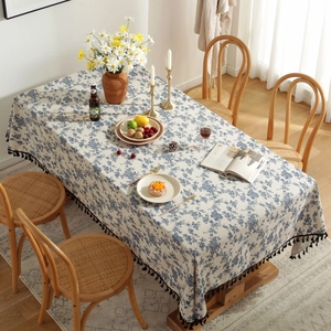 Detail of blue floral cotton linen tablecloth featuring decorative black tassels on edges
