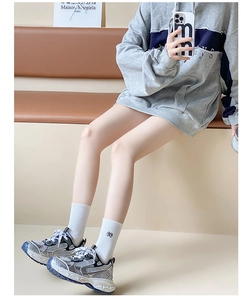 Close-up of white mid-calf socks with cute embroidery paired with grey sports shoes