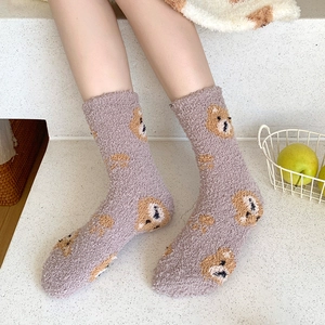 Close-up of purple coral fleece socks with cute bear pattern worn in a cozy home setting
