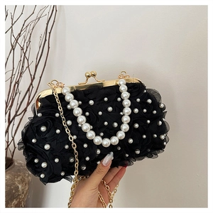Détail du sac à main en dentelle noire avec fleurs en relief, perles et bandoulière dorée