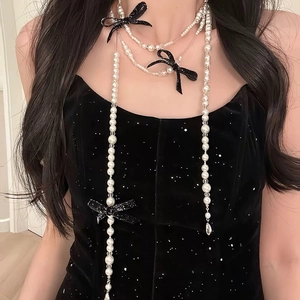 Detail of elegant pearl body chain with black sequin bows on a velvet dress