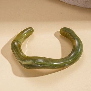 Macro view of green marble-textured acrylic irregular wavy open cuff bracelet