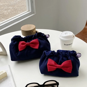 Detailed view of navy waffle fabric cosmetic bags with large red bows and jewel zipper