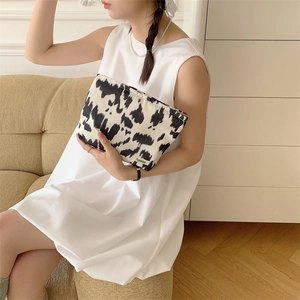 Close-up of portable cotton makeup bag with black and white cow print and brand label