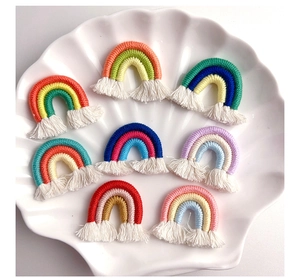 Handmade cotton rope rainbow charms with tassels displayed on a white shell plate
