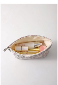 Flat lay of floral cosmetic bag showing interior capacity with various makeup products