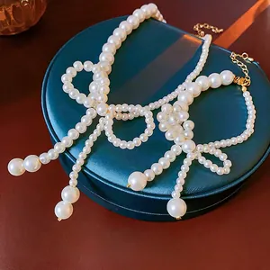 Elegante collana di perle con fiocco e chiusura dorata su espositore in velluto