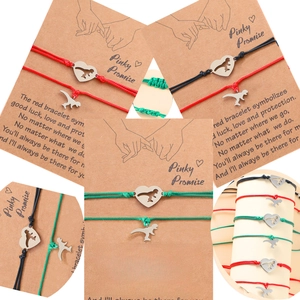 Close-up of Pinky Promise braided cord bracelets with dinosaur and heart charms