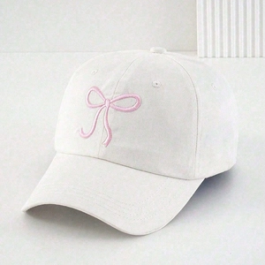 White baseball cap featuring pink embroidered bow design with adjustable back strap