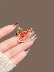 Macro shot of a red enamel rocking horse brooch with white sparkling rhinestones
