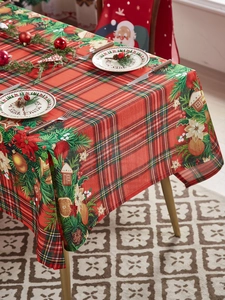 Detail of red plaid Christmas tablecloth with poinsettia, pine cones and gingerbread house