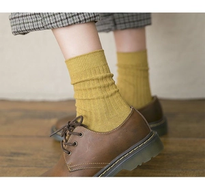 Detail of mustard yellow ribbed crew socks paired with vintage brown leather shoes