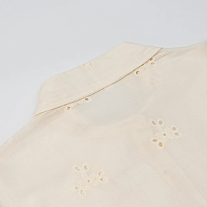 Macro view of lace embroidery details and linen texture on the beige shirt collar