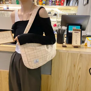 Close-up of beige plaid woven shoulder bag featuring a half-moon shape and SR fabric label
