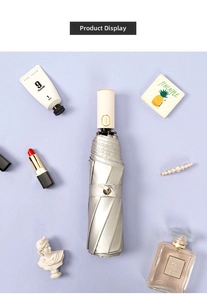 Flat lay of a silver automatic sun umbrella with pearl white handle and golden button