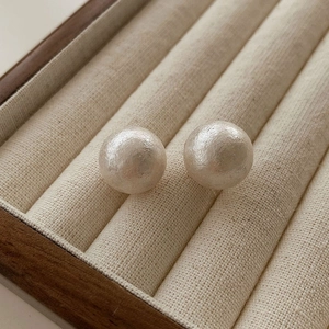 Macro shot of large creamy cotton pearls with textured finish in a beige jewelry box